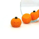 3D orange jack-o'-lantern charm with carved face and green stem, shown on a white background.