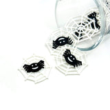 White spider web charm with a black spider detail, shaped in a circular web design, shown on a white background.