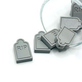 RIP tombstone charm with engraved lettering and a textured stone design, shown on a white background.