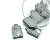 Skeleton tombstone charm featuring a skeleton hand above a detailed gravestone, displayed on a white background.
