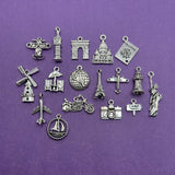 A collection of 17 mixed silver-toned travel-themed charms in various sizes and shapes, displayed together.