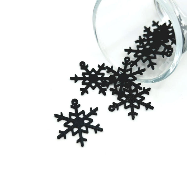 Black snowflake charm with symmetrical, intricate cut-out design, approx. 22×26 mm, shown against a white background.