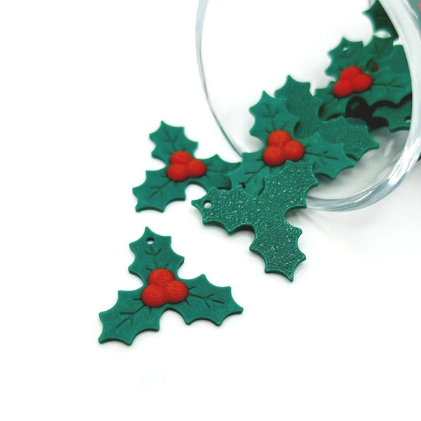 Green holly leaf ornaments with red berries on a white background