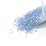 Small blue beads spilling out of a clear container on a white background