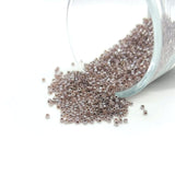 Small glass jar filled with metallic beads on a white background