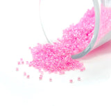 Pink beads spilling out of a clear container on a white background