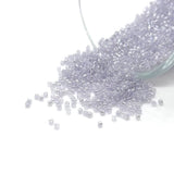 Clear glass seed beads spilling out of a container on a white background
