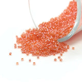 Small glass beads spilling out of a clear container on a white background