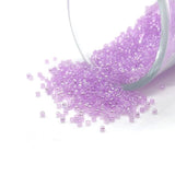 Purple beads spilling out of a clear container on a white background