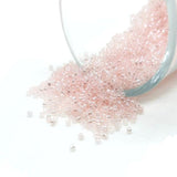 Small container of pink beads spilling out on a white background