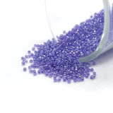 Purple beads spilling out of a container on a white background