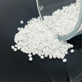 White beads being poured from a container onto a black surface