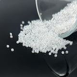 Clear glass beads spilling out of a transparent container on a black surface