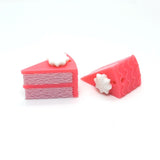 Two strawberry pink cake charms on a white background