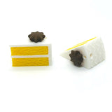 Two small yellow cake charms on a white surface