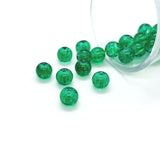 Green beads spilling out of a container on a white background