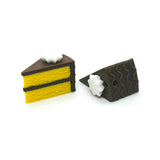 Two miniature cake slices with yellow layers and brown frosting on a white background