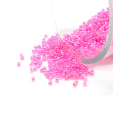 Pink beads spilling out of a container on a white background
