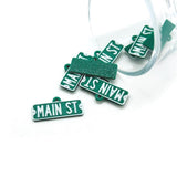 Green 'MAIN ST' street sign pendants on a white background