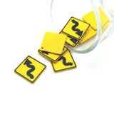 Yellow road sign-shaped charms with black wavy lines on a white background
