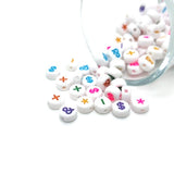 White beads with colorful symbols scattered on a white background