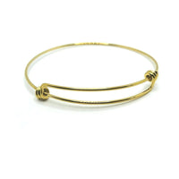 A slim, gold-tone expandable wire bangle with overlapping ends, shown flat on a white background to highlight its reflective surface and sleek profile.