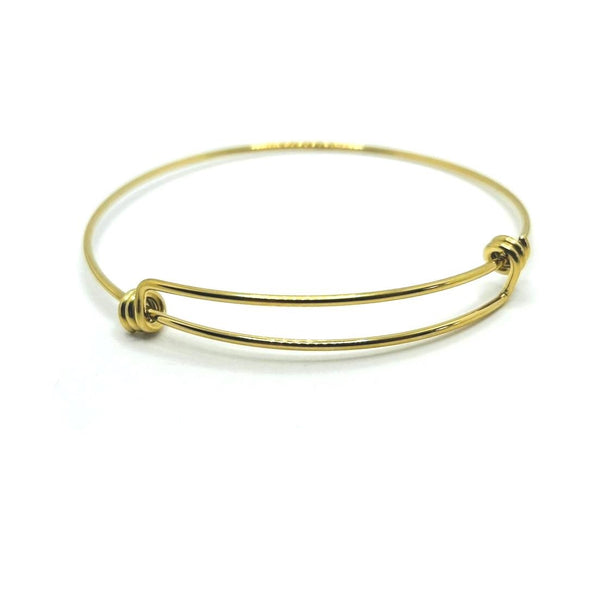 A slim, gold-tone expandable wire bangle with overlapping ends, shown flat on a white background to highlight its reflective surface and sleek profile.