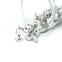 A pile of small shiny silver glue-on anchor bails with flat round pads and looped tops, displayed on a white background.