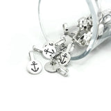 A pile of small shiny silver glue-on anchor bails with flat round pads and looped tops, displayed on a white background.