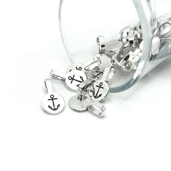 A pile of small shiny silver glue-on anchor bails with flat round pads and looped tops, displayed on a white background.