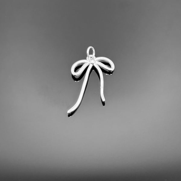 A polished sterling silver bow charm, approximately 20×13 mm, with a small attachment hole, displayed on a black background.