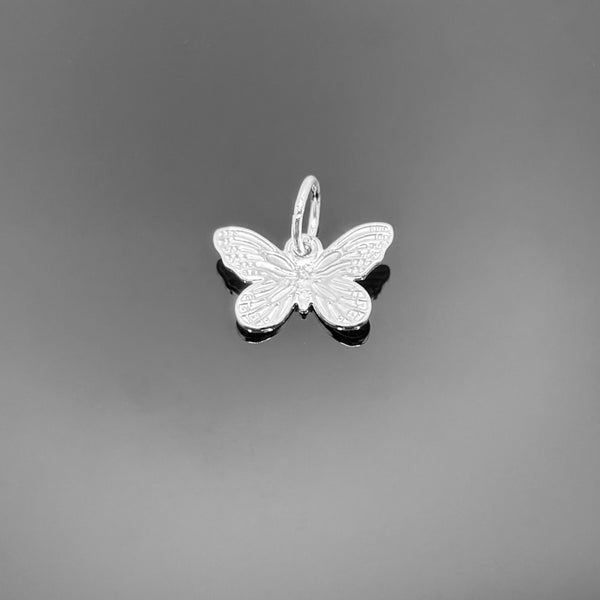 A small sterling silver butterfly charm with finely detailed wings and a top loop, measuring approximately 8×12 mm, displayed on a black background—ideal for polished, minimalist jewelry designs.