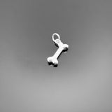 A small sterling silver dog bone charm with a polished finish and top loop, approximately 11×6 mm, displayed on a clean black background—ideal for pet lover jewelry designs.