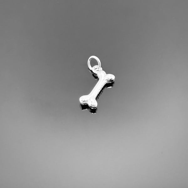 A small sterling silver dog bone charm with a polished finish and top loop, approximately 11×6 mm, displayed on a clean black background—ideal for pet lover jewelry designs.