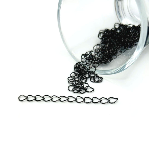 Gunmetal-gray metal chain extender (approx. 5 cm long) with oval links and small clasp, displayed on a wood-textured neutral background.