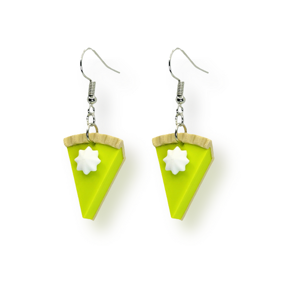 Pair of miniature key lime pie slice earrings with green filling and whipped cream details, displayed on a white background.